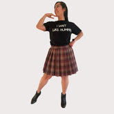 Person wearing a black t-shirt with text and a brown plaid skirt on a white background