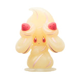 Alcremie Pokemon translucent figurine with a yellow body, red cheeks, and pink accents