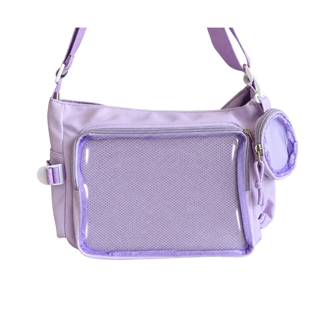A light purple crossbody ita bag with a large clear mesh front pocket, a side buckle strap, and a small matching zippered pouch, shown on a plain white background.
