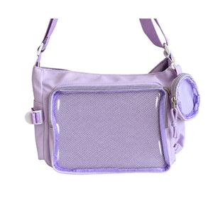 A light purple crossbody ita bag with a large clear mesh front pocket, a side buckle strap, and a small matching zippered pouch, shown on a plain white background.