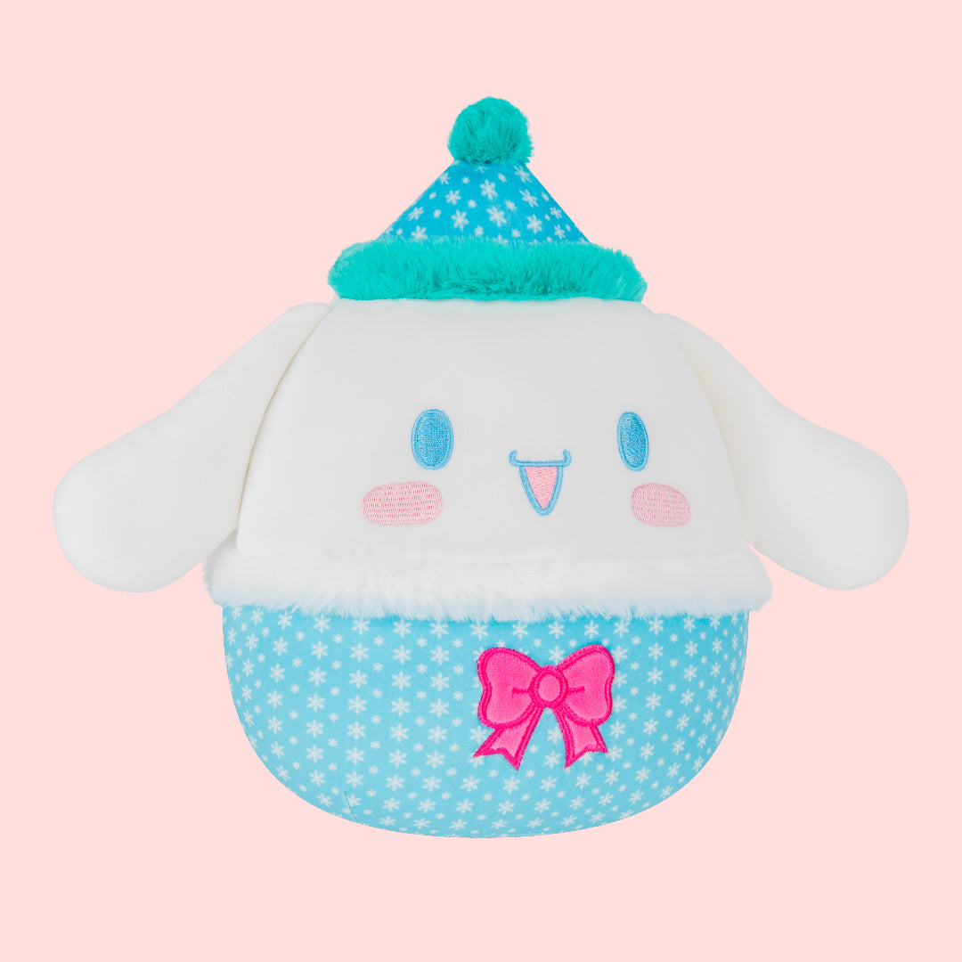 Cute plush toy with a blue polka dot hat and pink bow on a pink background