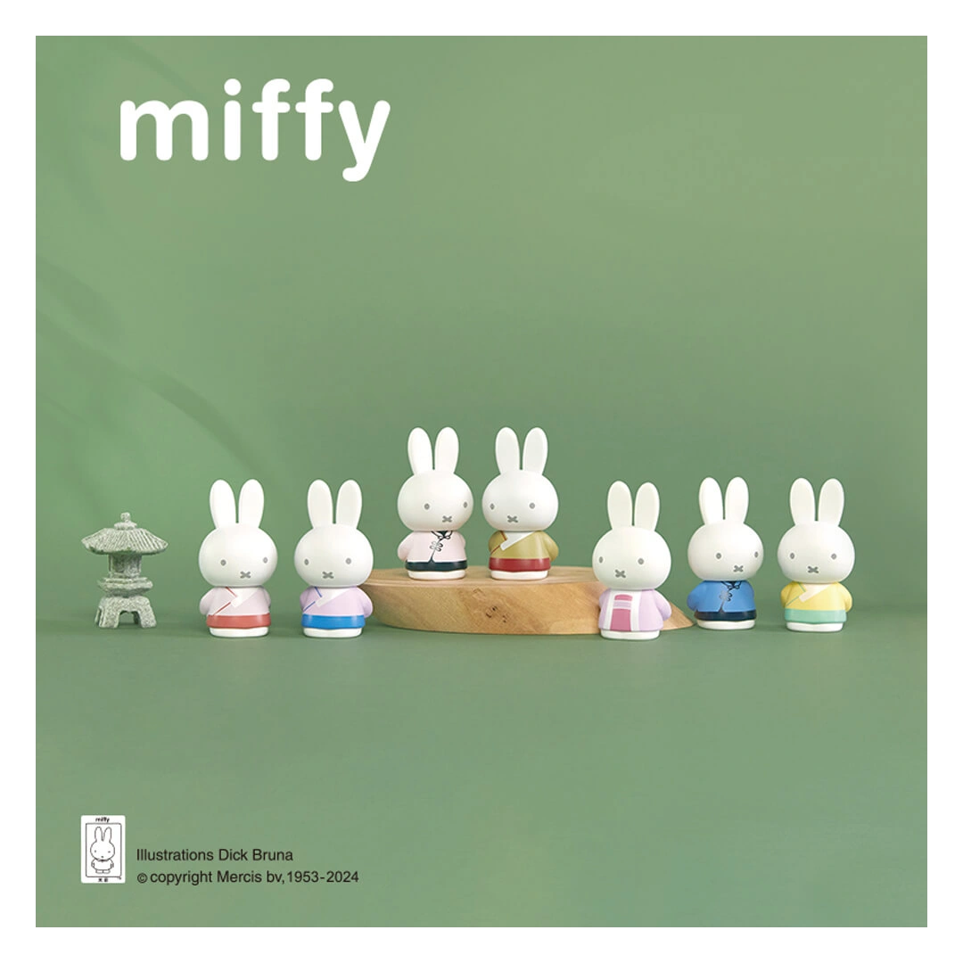 Miffy figurines on a wooden stand with a green background