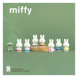 Miffy figurines on a wooden stand with a green background
