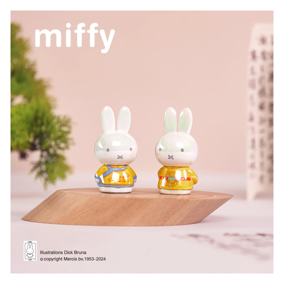 Two small rabbit figurines in yellow outfits on a wooden platform with 'miffy' branding.