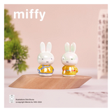 Two small rabbit figurines in yellow outfits on a wooden platform with 'miffy' branding.