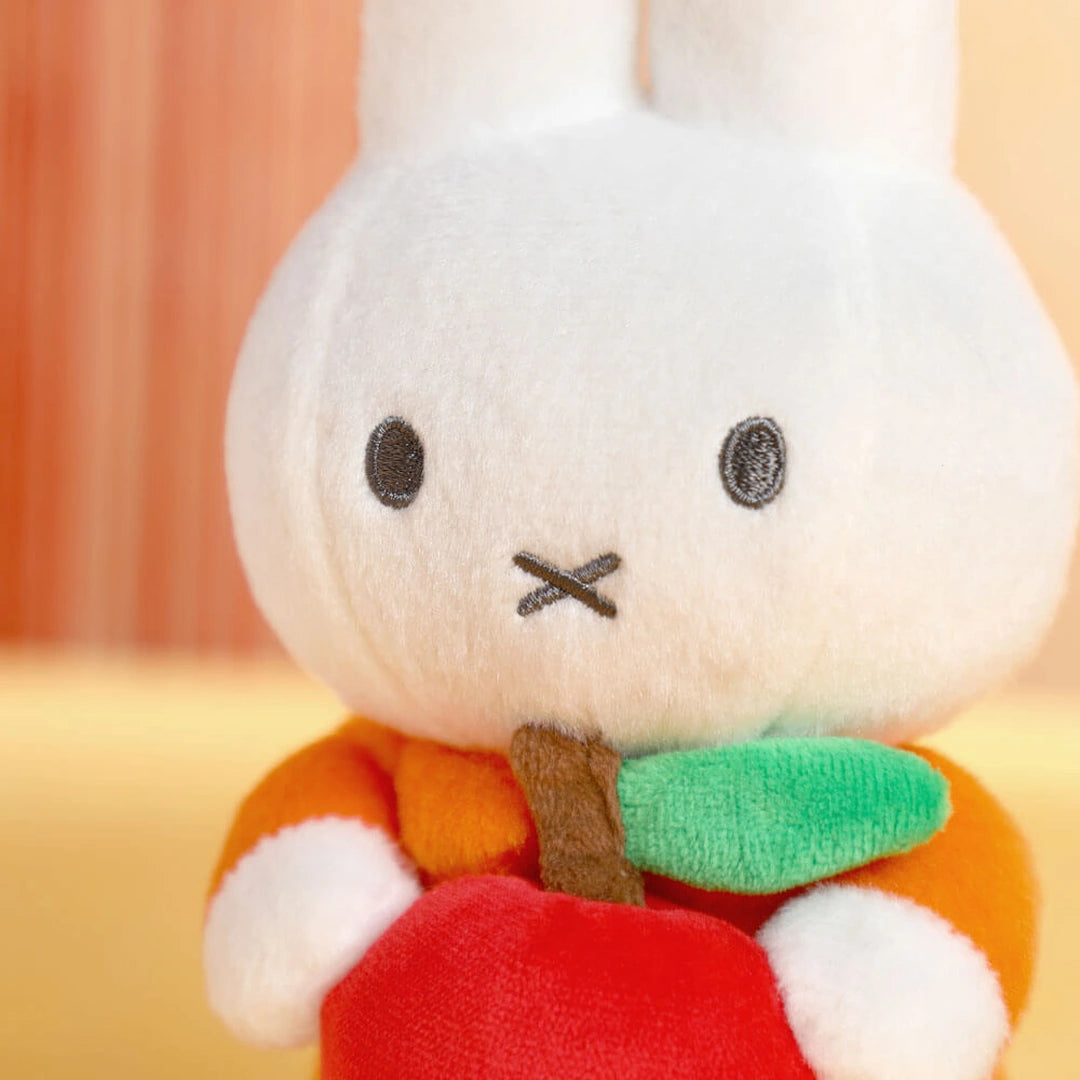 Miffy the bunny Plush toy with a carrot on an orange background