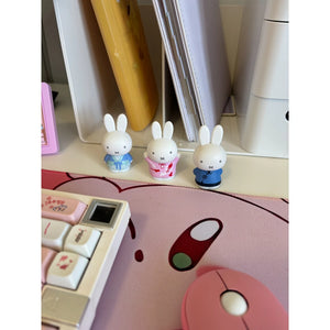 Three small rabbit figurines on a desk with stationery items.