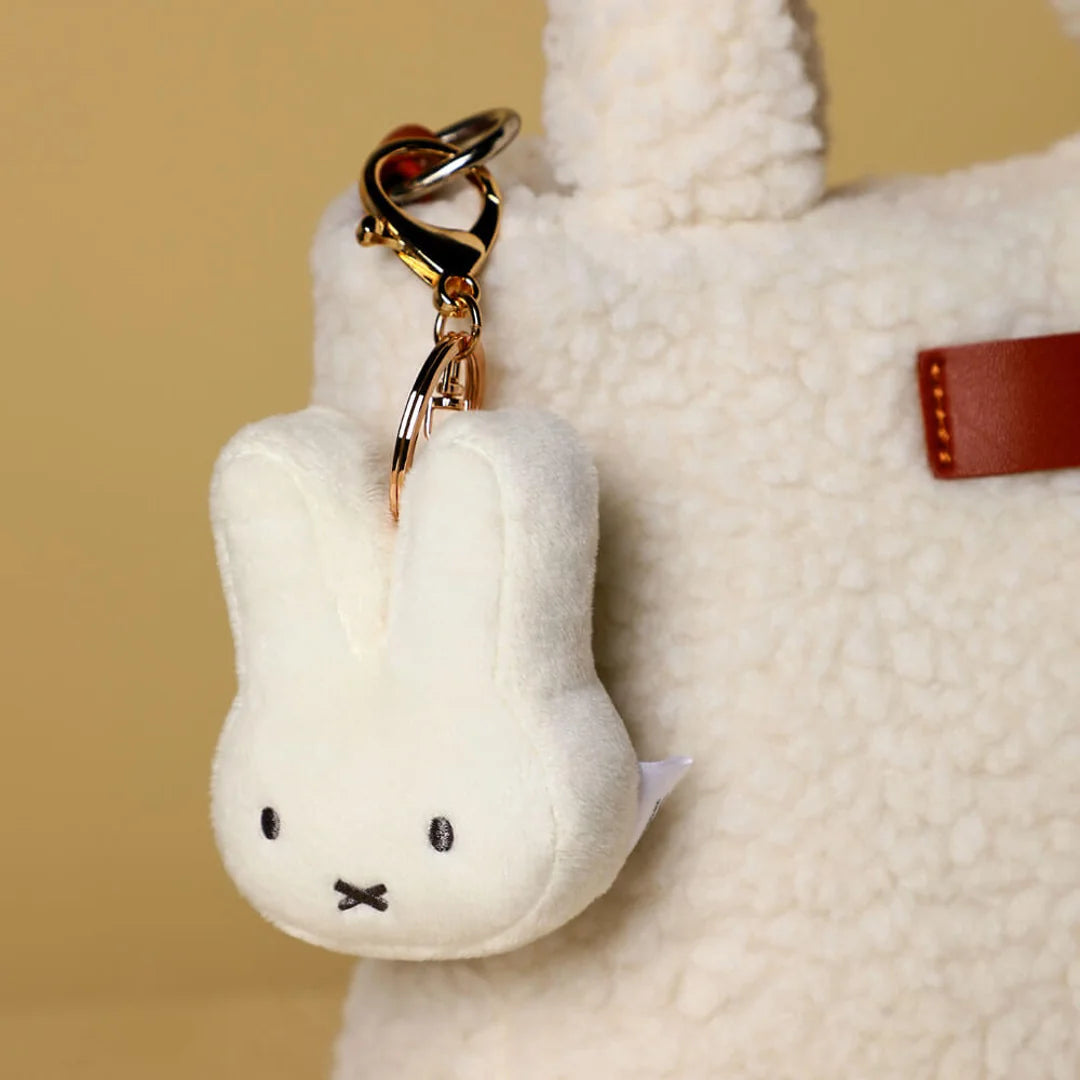 White plush Miffy Bunny keychain with gold ring attached to a bag