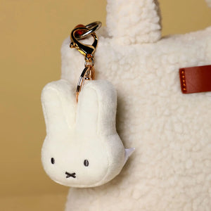 White plush Miffy Bunny keychain with gold ring attached to a bag
