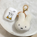 Miffy face plush keychain next to AirPods case showing compact size