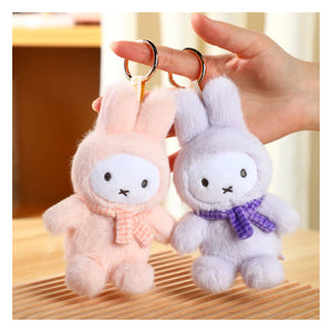 Two plush Miffy bunny keychains, one pink and one white, held by a hand. These are part of the miffy blind box macaron series