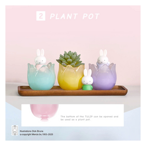 Three colorful rabbit-shaped plant pots on a wooden tray with a pink background.