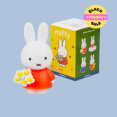 Miffy figurine Miffy with a red dress and flower bouquet next to its packaging