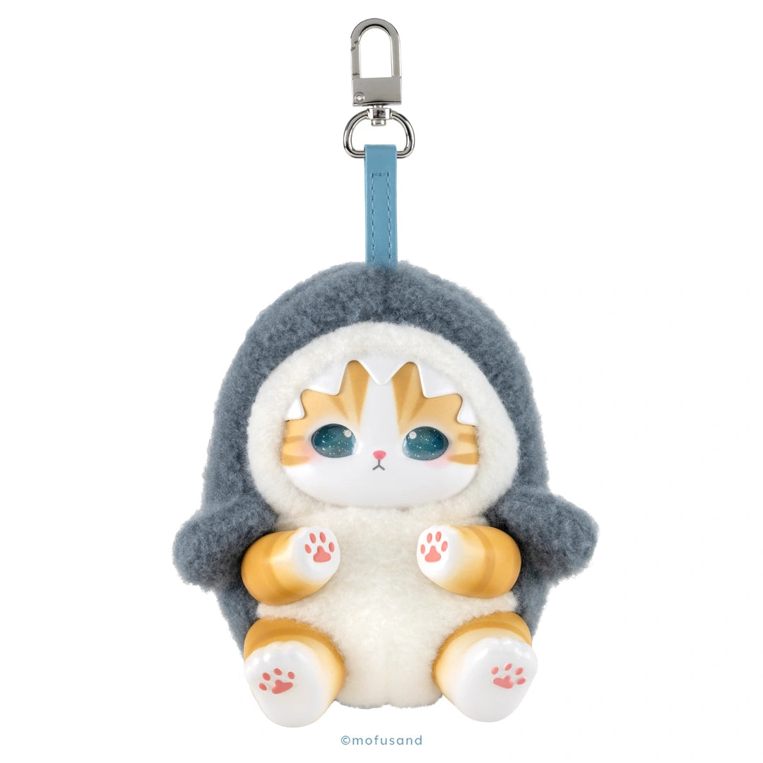 A plush cat-shaped keychain or bag charm with a gray shark hood, white body, orange-tan face and paws, blue strap, and silver metal clasp on a plain white background.