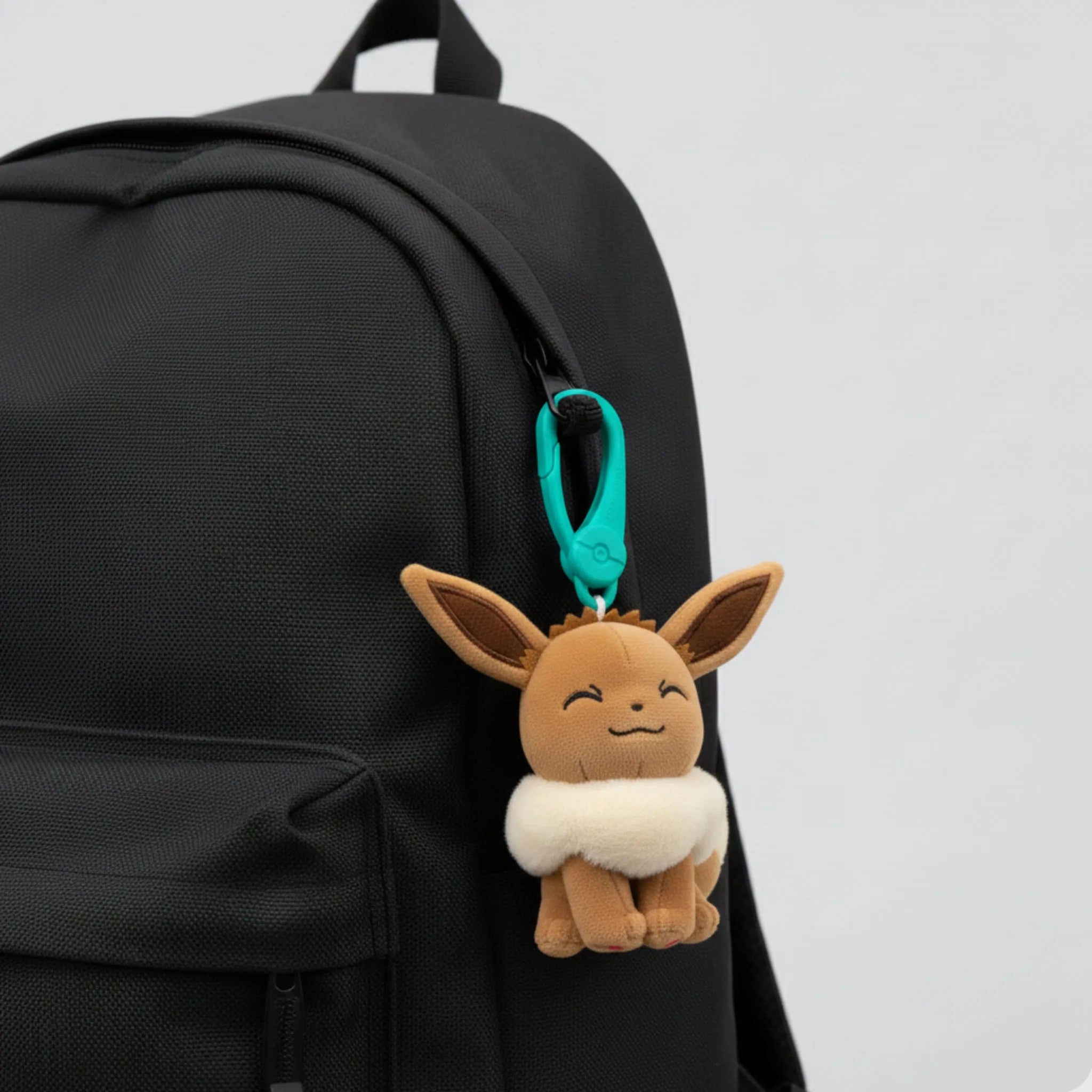 Plush Eevee keychain attached to a black backpack. Pokemon bag clip