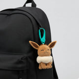 Plush Eevee keychain attached to a black backpack. Pokemon bag clip
