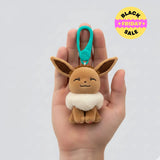 Plush keychain of a cartoon character held in a hand against a white background