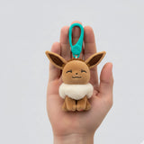 Plush keychain of a cartoon character held in a hand against a white background