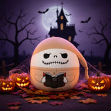 Plush toy with a skull design holding a book on a white background