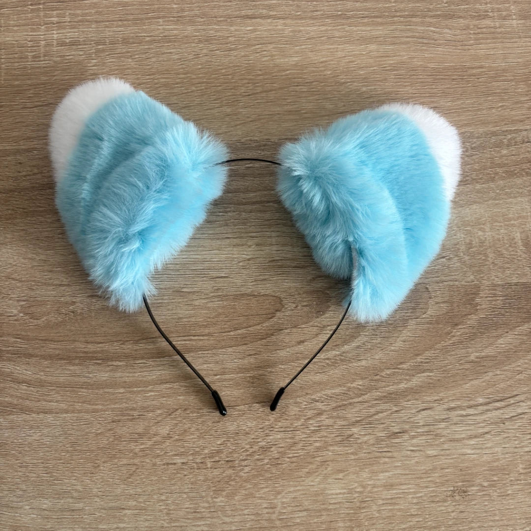 Light blue and white faux fur cat ears headband on a light wood background.