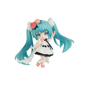 A chibi-style vinyl figure of Hatsune Miku with long turquoise hair, wearing a white dress with black bows and floral hair accessories, posed against a plain white background.