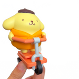 Yellow dog-like character on a scooter held by a hand against a white background