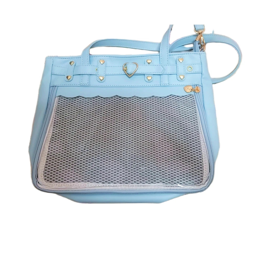 A light blue faux-leather ita pin handbag with a scalloped edge, gold-tone studs, a heart-shaped clasp, and a clear mesh front pocket, shown on a plain white background.