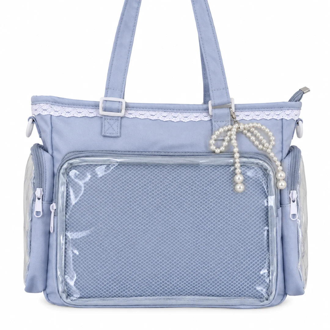 A light blue pin bag with a large clear mesh front pocket, side zippered pockets, top handles, a lace trim detail, and a pearl beaded bag charm.