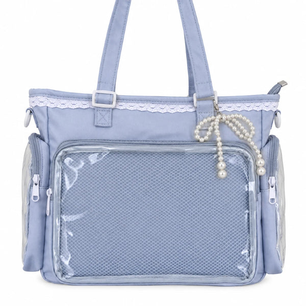 A light blue pin bag with a large clear mesh front pocket, side zippered pockets, top handles, a lace trim detail, and a pearl beaded bag charm.
