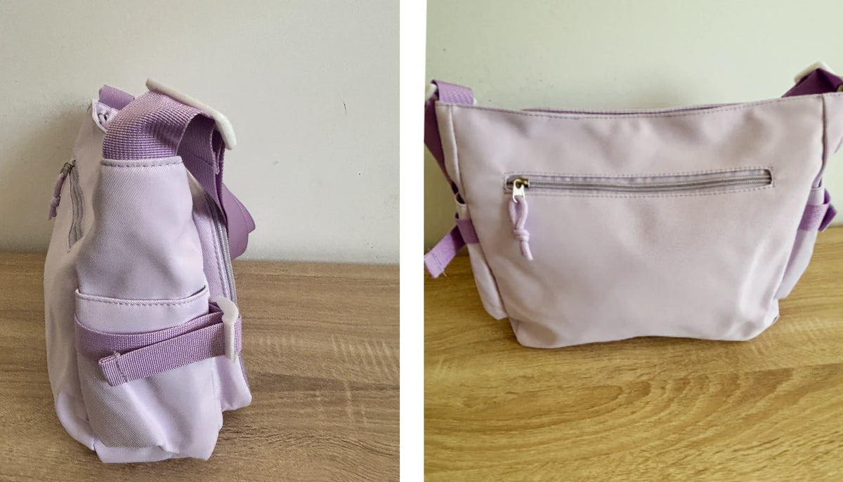 A light lavender canvas ita crossbodybag shown in two views: a side profile on a wooden table against a plain wall, and a front view showing a zippered pocket, on a wooden table against a pale green wall.