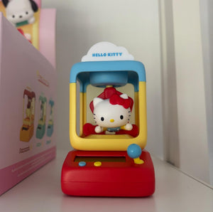 Hello Kitty toy in a red and yellow machine with a pink box in the background