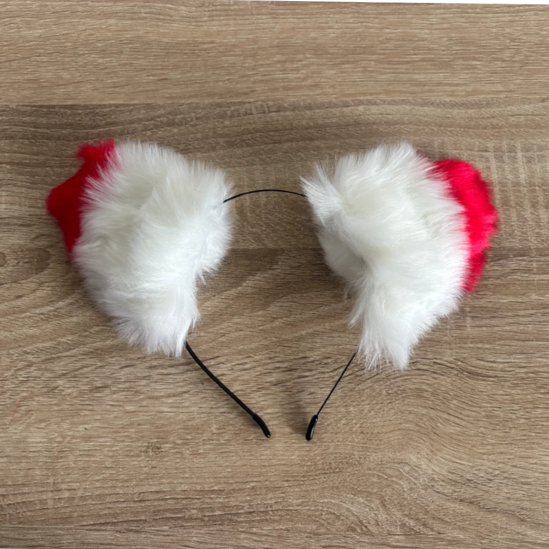 A fluffy faux-fur ears in white and red, resting on a light brown wood-grain surface.