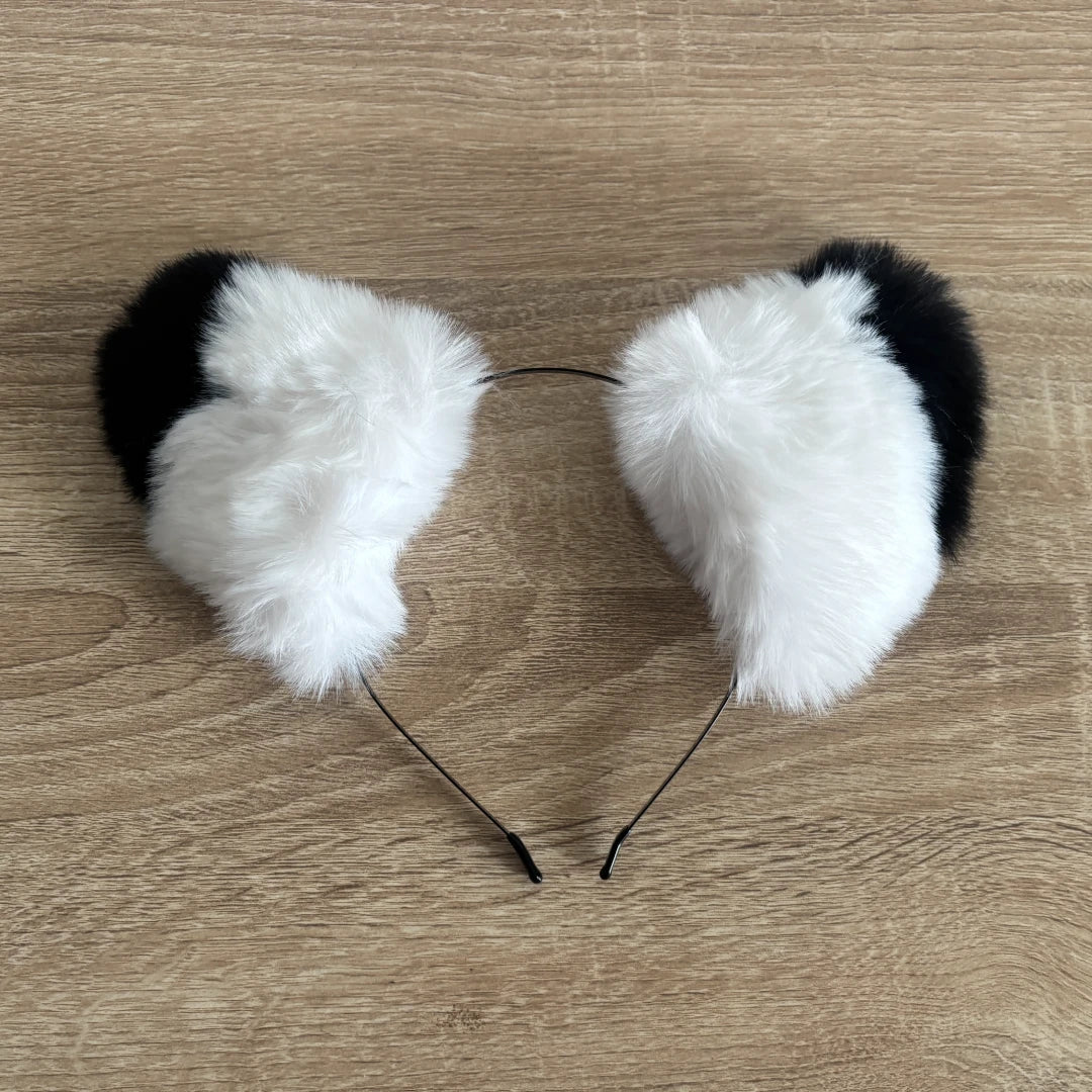 Black and white faux fur cat ears headband on a light brown wood grain background.