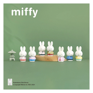 Miffy figurines on a wooden stand with a green background