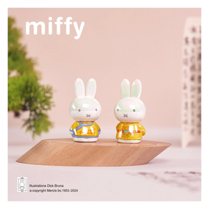 Two small rabbit figurines in yellow outfits on a wooden platform with 'miffy' branding.