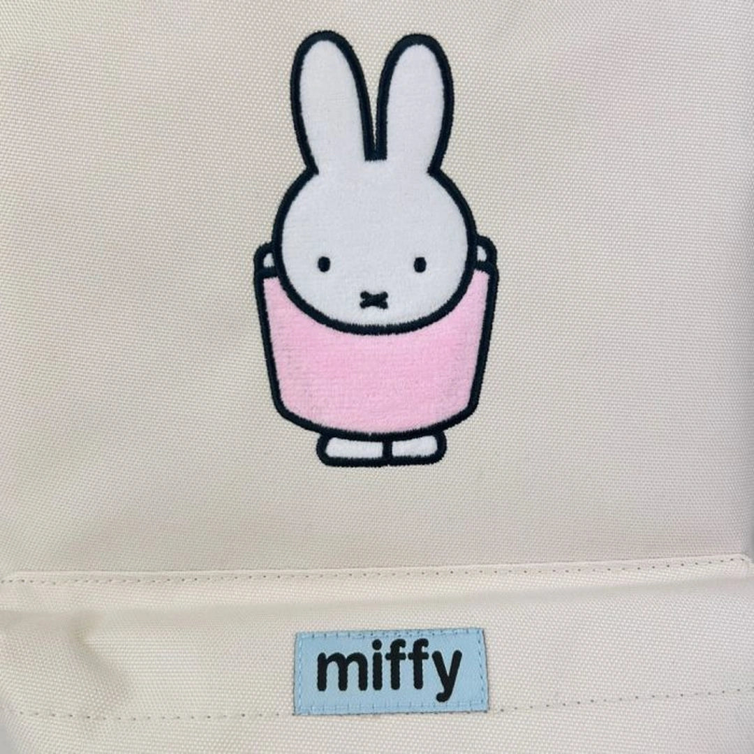 Backpack close up of Embroidered Miffy rabbit character with a pink dress on a beige background, featuring the brand 'miffy'. 