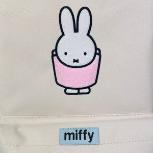 Backpack close up of Embroidered Miffy rabbit character with a pink dress on a beige background, featuring the brand 'miffy'. 