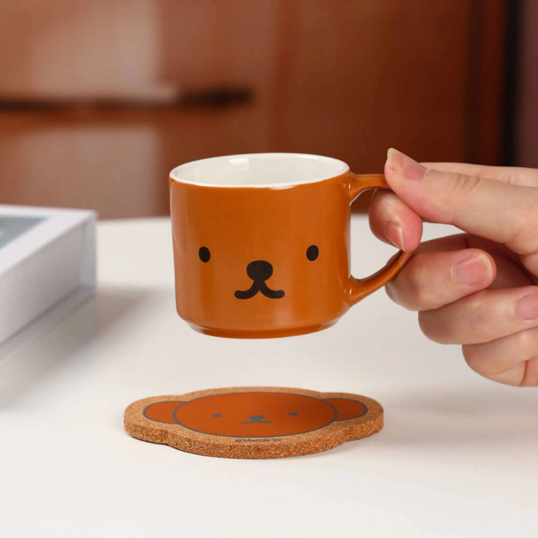 Person holding a brown mug with a bear face design . Miffy blind box 
