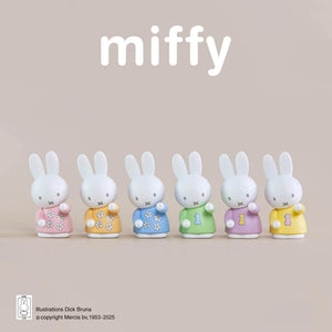 Six Miffy figurines in colorful outfits on a beige background with 'miffy' branding.