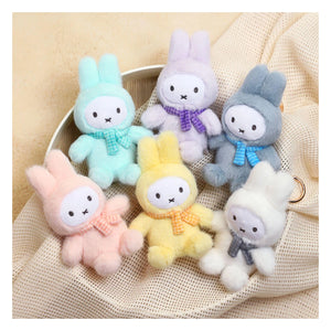 Set of colorful plush Miffy  rabbit toys with scarves on a beige fabric. Miffy blind box macaron series 